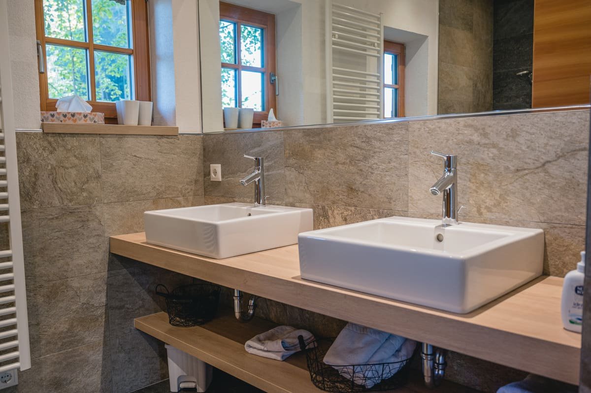 Badezimmer mit Doppelwaschbecken, Spiegel und Fenster