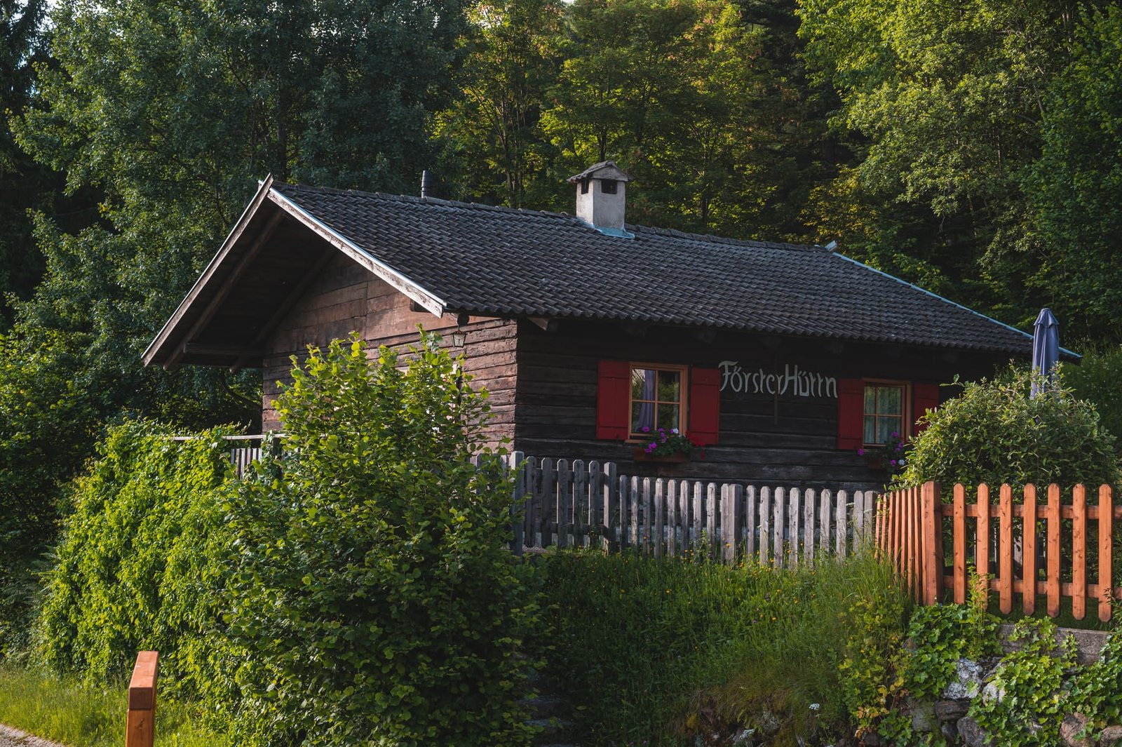 Die Försterhütte zwischen Bäumen und Zaun auf der Brünnlwiese