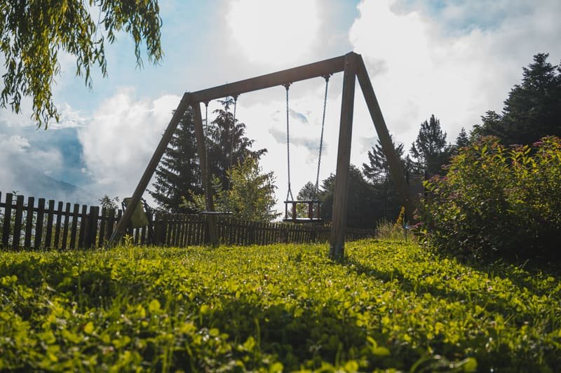 Holzschaukel auf der Wiese im Gegenlicht